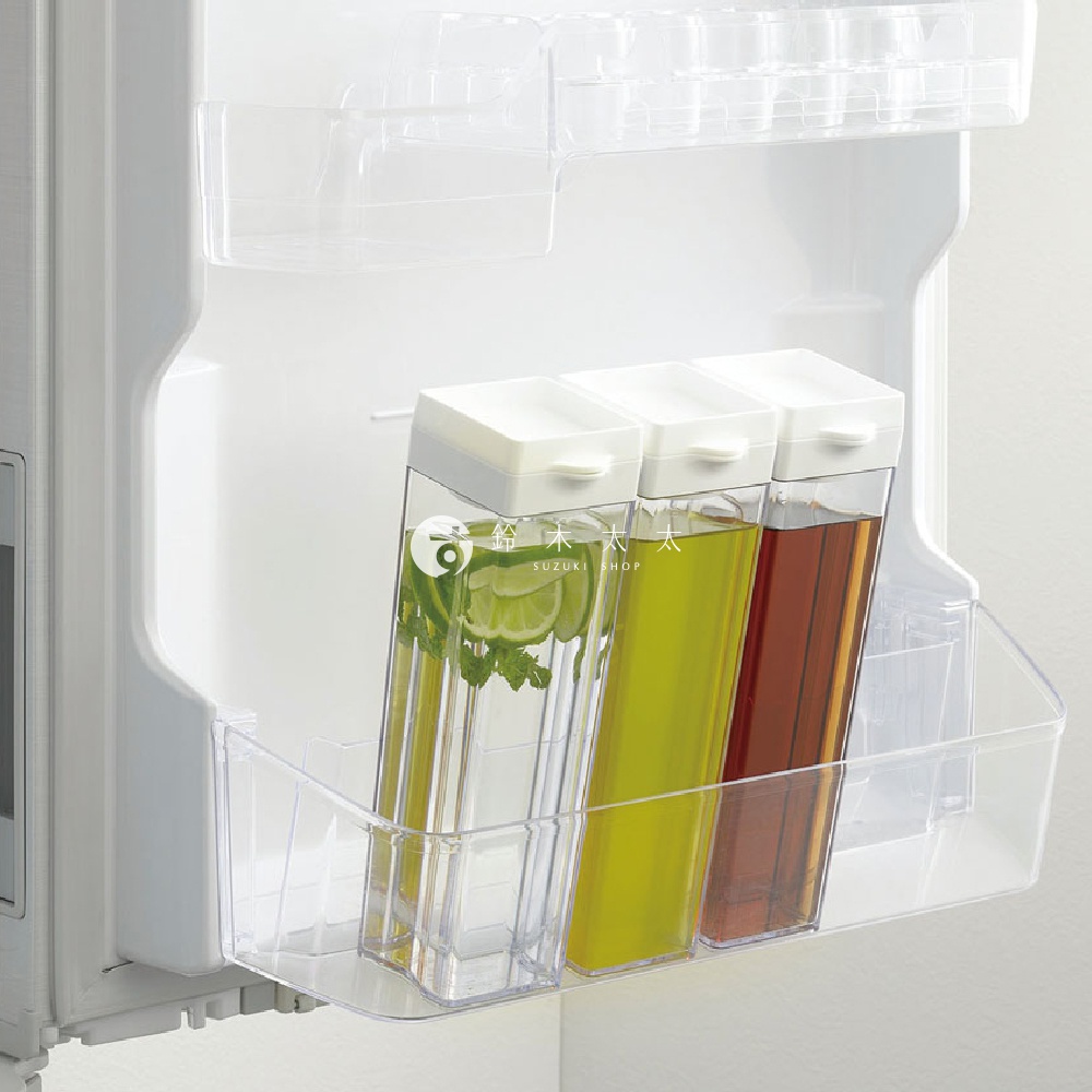 冰箱門架上擺放著三個透明直立式水瓶，瓶內裝有不同顏色的液體，最左邊的水瓶內有檸檬片與薄荷葉，瓶身上印有日文與英文 SUZUKI SHOP 字樣。