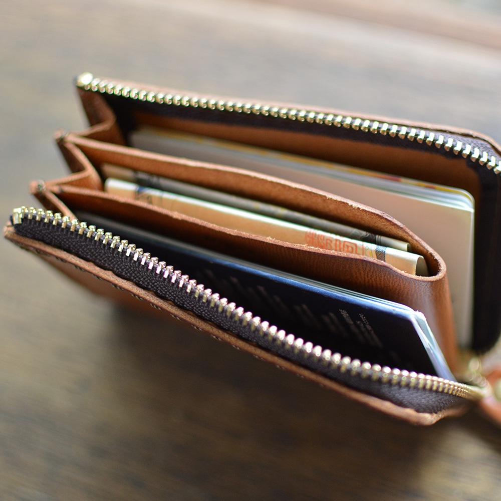 職人手作皮革Organ口袋拉鍊短夾，展現自然皮革紋理與溫潤的棕色調，內部包含多個卡槽與紙鈔夾層，並以金屬拉鍊完整收納，設計簡約實用。