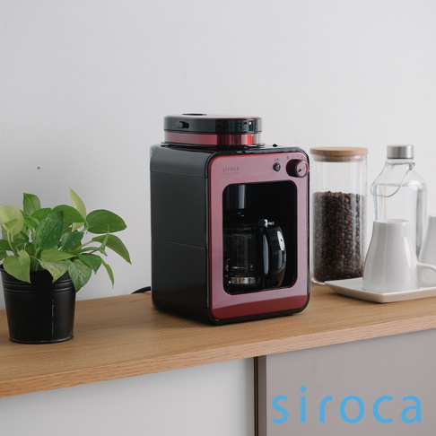 SC-A1210 自動研磨咖啡機，採用黑紅配色，機身線條簡潔。上方為研磨器，下方是玻璃咖啡壺。整體以塑膠和金屬材質為主。