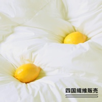 潔白蓬鬆的雲絨被，表面有細緻的縫線，兩顆黃色檸檬散落在被褥中，營造柔軟舒適的視覺效果。