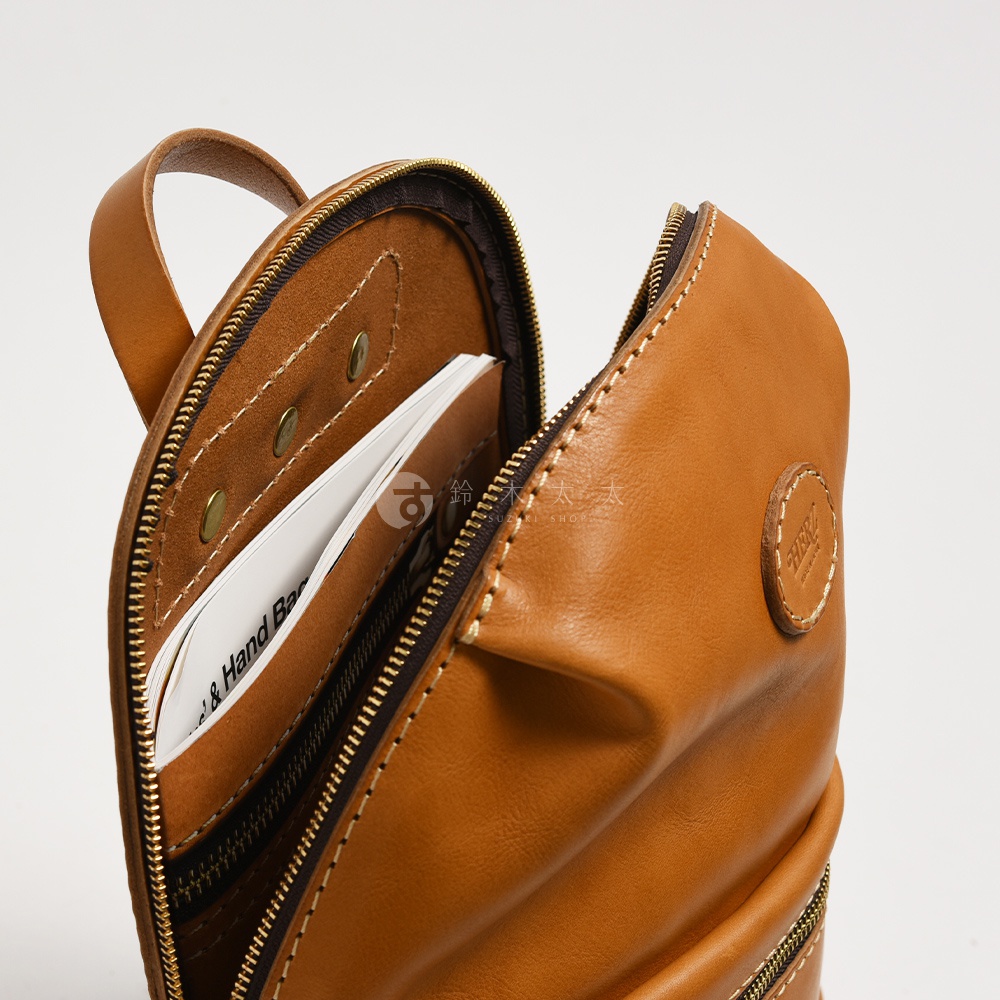 棕色皮革大開口圓角後背包，展示內部隔層與部分卡片。包身有明顯車縫線與金色拉鍊。