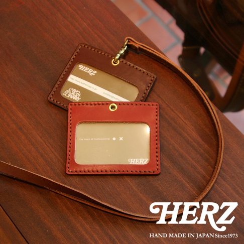 兩個職人手作皮革橫式證件識別夾，一個為紅棕色，另一個為深棕色，皆有透明證件窗及吊繩。