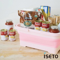 粉色與白色相間的伸縮提籃，籃中裝有Kirkland品牌穀物、Campbell's玉米濃湯罐頭、番茄醬罐及其他食品雜貨。