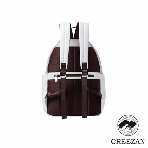 這是一款 CREEZAN CRUISER 系列後背包的背面視圖，主體採用棕色織物與白色皮革拼接設計，配有白色寬版可調式背帶，背部中央設有一條橫向拉鍊口袋，整體呈現簡約時尚的質感，右下角印有 CREEZAN 品牌標誌與圖騰。