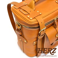 職人手作皮革大型三用旅行後背包，棕褐色，展示包的側面細節，包括拉鍊、皮帶扣、铆釘和縫線，質感厚實。