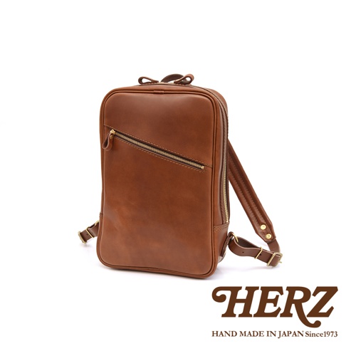 職人手作皮革長方型多口袋後背包 R-17，採用深棕色皮革製成，設有斜向拉鍊口袋和頂部提把，搭配金屬拉鍊與扣環，簡約實用。