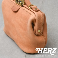 日本HERZ職人手作皮革Organ鎖孔式大開口肩背包，淺棕色皮革材質，鎖扣細節，以視覺特寫展示。