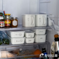 白色長方型深型密封蓋琺瑯保存容器，帶有銀色把手，表面有日文手寫標記，與其他白色保存容器和玻璃罐一同擺放在冰箱內。