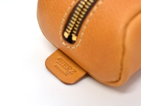 職人手作皮革圓角收納筆袋 (KP-1)，呈現自然的淺棕色皮革質感，搭配金屬拉鍊。皮革上有壓印的品牌標誌「HERZ」及「MADE IN JAPAN」。