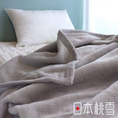 舒眠雙面四季毯，淺灰色，材質柔軟，觸感舒適，毯邊有細緻縫線，搭配白色枕頭與床鋪，呈現溫馨居家氛圍。