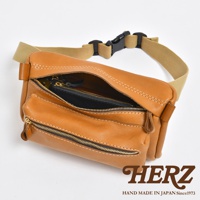 棕色皮革製作的兩用腰掛斜背包，設有拉鍊主袋和前袋，配有可調節的卡其色織帶和黑色塑膠扣。