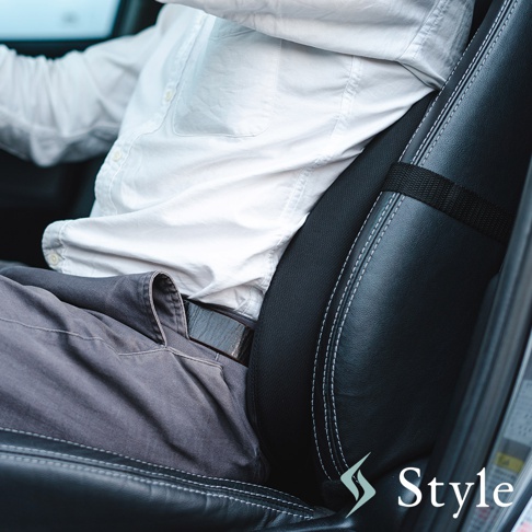 黑色皮革車用靠腰椅，帶有白色縫線，固定在汽車座椅上，一名男子穿著白色襯衫和灰色褲子坐在其中。