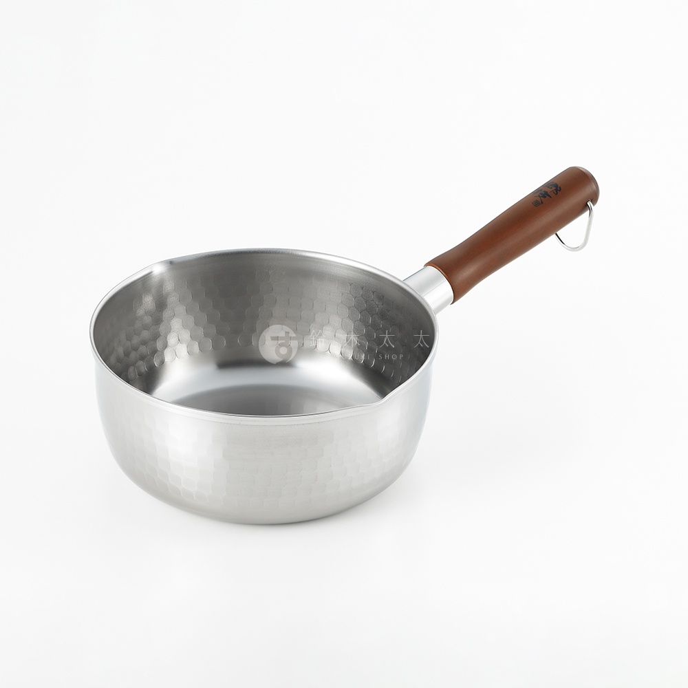 鄉技不鏽鋼單柄雪平鍋，鍋身呈現金屬銀色，表面有槌目紋路。木質手柄為深棕色，末端有一個銀色掛環。