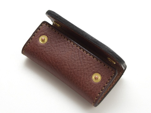 職人手作咖啡色皮革鑰匙包，附有兩個黃銅按扣和縫線細節，展現皮革紋理。
