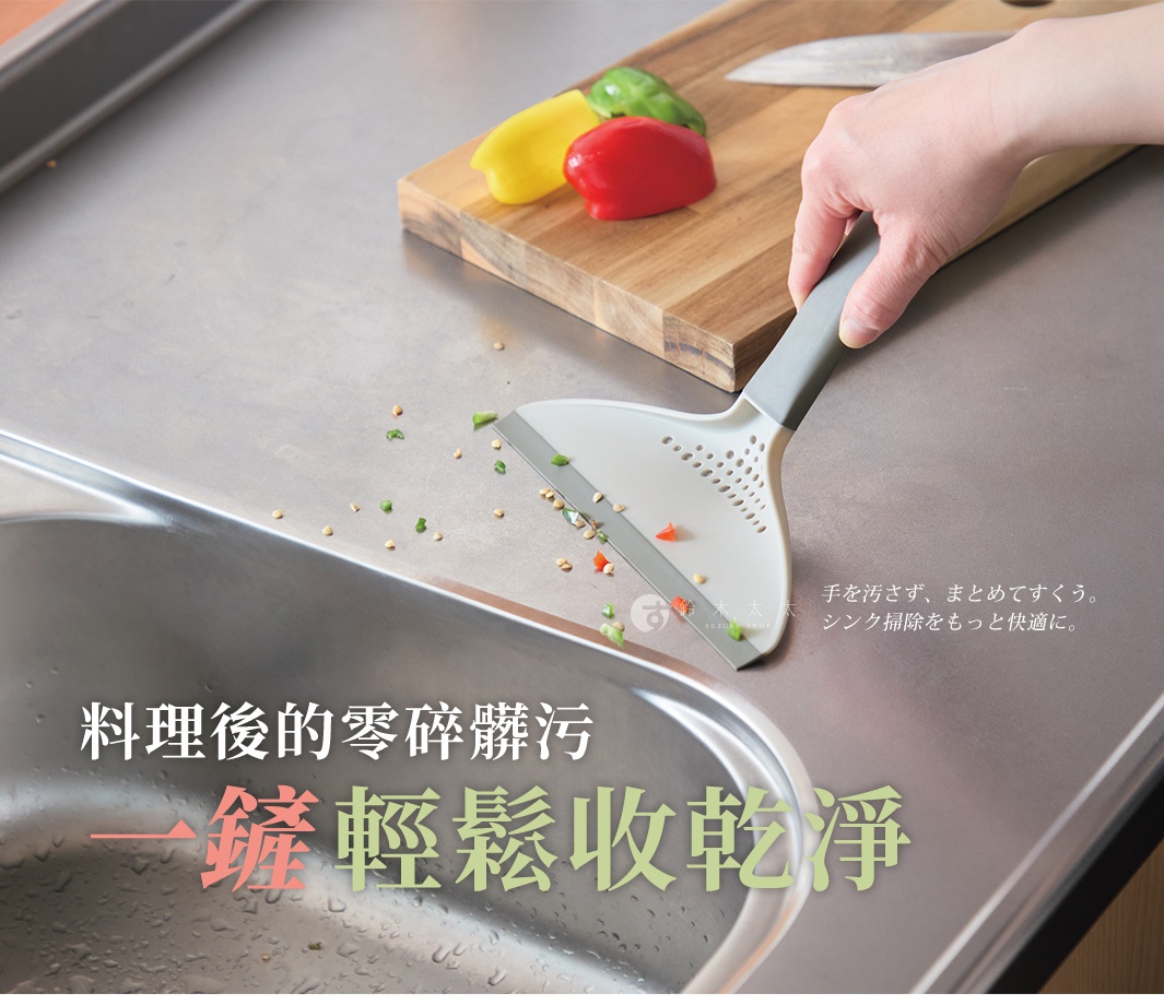 這張照片呈現一人手持一把灰白色的多用途清潔刮鏟，正在清理流理檯面上料理後留下的碎屑與髒污，將食材殘渣集中掃入水槽中，旁邊的砧板上放置著紅、黃、綠三色甜椒，畫面強調這款清潔工具能讓清理過程保持雙手潔淨並輕鬆整理環境。