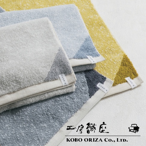 棉麻混紡雙色快乾毛巾，展示淺灰、淺藍、深灰及鵝黃四種顏色，毛巾表面為絨毛材質，邊緣有幾何撞色設計，並帶有 CUON.E 品牌標籤。