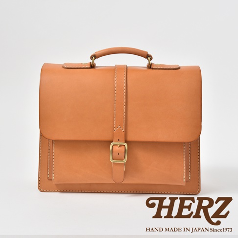 職人手作皮革三用單扣商務後背包，淺棕色，經典公事包造型，以單扣和皮帶固定，整體呈現復古風格。