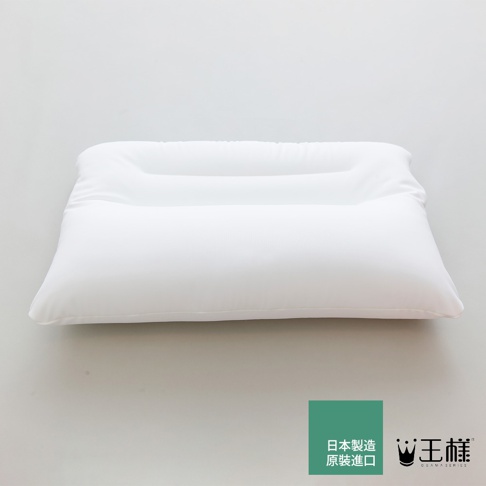 一張純白色頸椎枕，枕面有明顯的凹槽設計，材質看起來光滑柔軟，左下角有一個綠色方塊，上面印有日文「日本製造 原裝進口」字樣，右側是「王樣」品牌標誌。