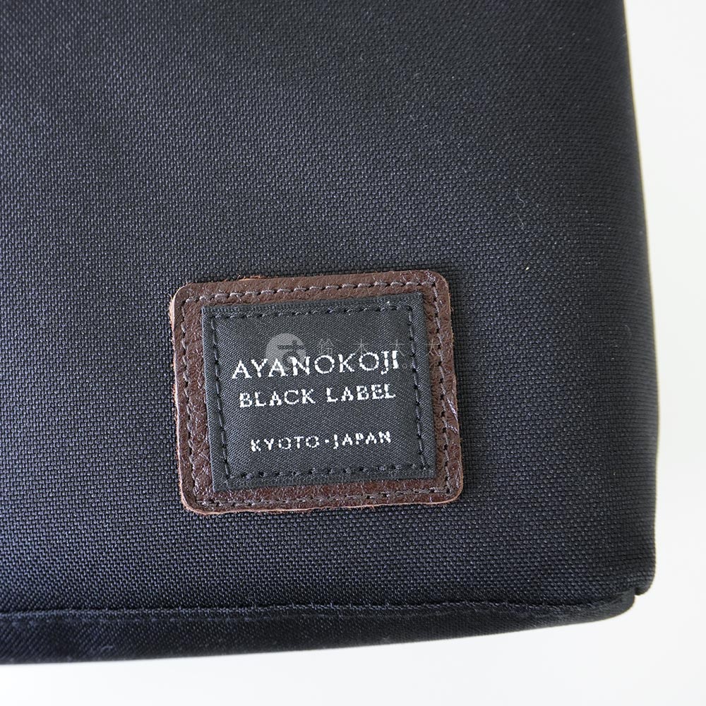 黑色布質包面上有一個咖啡色皮質標籤，上面印有 AYANOKOJI BLACK LABEL KYOTO · JAPAN 字樣