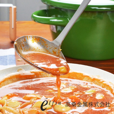 日製不鏽鋼橢圓尖嘴湯杓，杓內盛有紅褐色醬汁，正緩慢傾倒至白色盤中，盤內為同樣的醬汁及食材。背景為綠色鍋具。