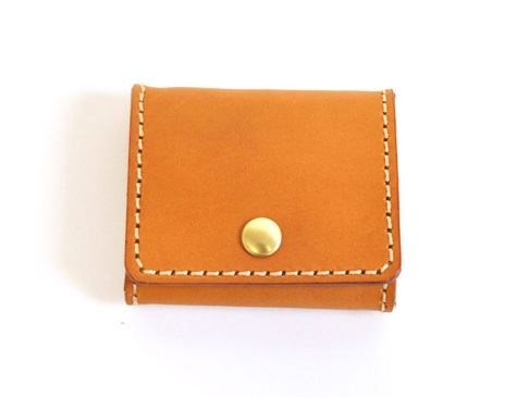 淺棕色皮革製成的箱型零錢包，以白色縫線手工縫製，中央有一個金色按扣。