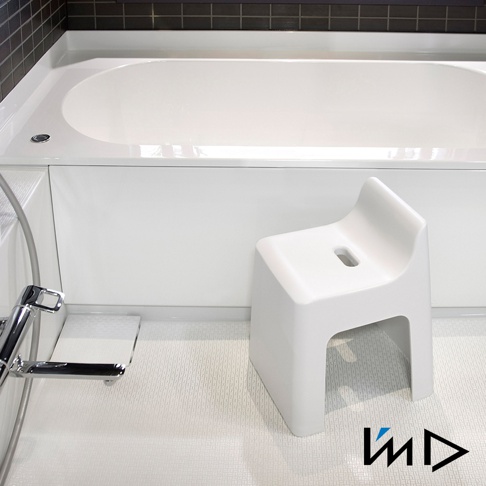 白色RETTO曲面一體簡約椅凳，塑膠材質，椅面中央有長方形孔洞，椅腳為開放式設計，置於浴室白色防滑地板上，旁為白色浴缸及金屬水龍頭。