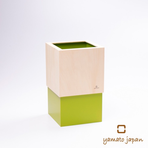一個由淺色木材製成的方型垃圾桶，頂部開口，內部為亮綠色。下半部為亮綠色的方型結構。