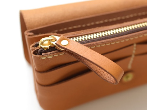 職人手作皮革旅行用多層次收納長夾，採用棕褐色皮革，配有金色拉鍊和皮質拉環，縫線精緻，內部有多層收納空間。