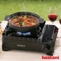 黑色金屬雙重防風卡式爐，爐上放置著裝有燉牛肉、紅蘿蔔及花椰菜的黑色鍋具，爐火為藍色火焰。