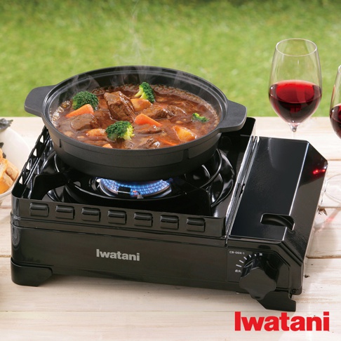 黑色金屬雙重防風卡式爐，爐上放置著裝有燉牛肉、紅蘿蔔及花椰菜的黑色鍋具，爐火為藍色火焰。