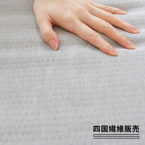 淺灰色透氣網布床墊，表面有細小密集的小圓點紋理，一隻手輕輕放在床墊上。