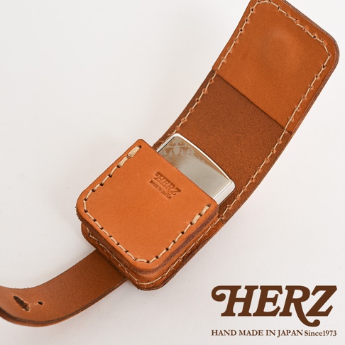 職人手作皮革原子釦型腰間小物收納包，採用天然皮革製成，呈現溫潤的棕褐色。設計簡潔，帶有原子釦設計，可固定於腰帶上，方便收納小物。表面壓印有品牌標誌及「MADE IN JAPAN」字樣。