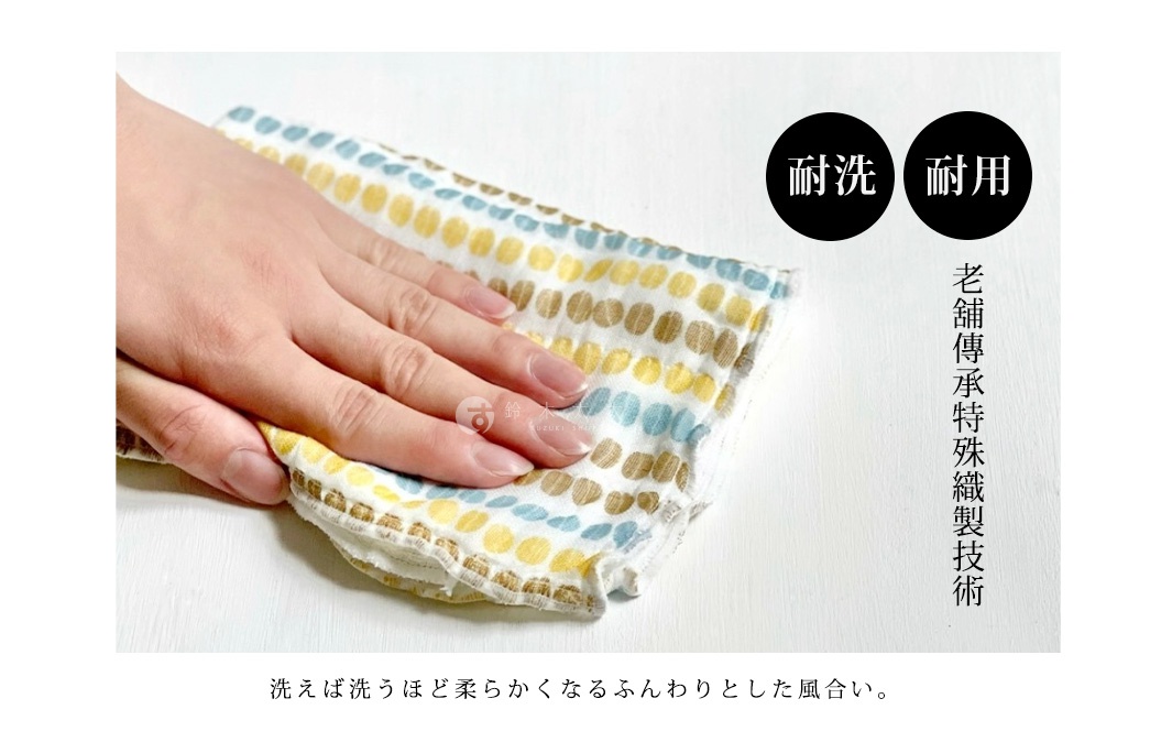 一只手正輕柔地撫摸著一塊友禪染多用途白雪拭巾，布料上印有黃色、藍色和棕色的圓點圖案，質地輕薄。