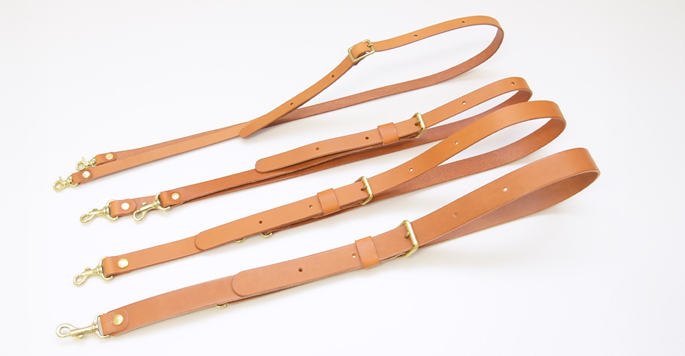 四條棕色皮革肩帶，帶有黃銅色的掛鉤和調整扣，整齊排列在白色背景上。