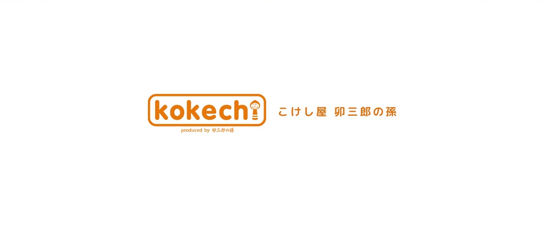 富士與火男木芥子開運擺飾組合，包含圓形橘色邊框的「kokechi」文字標誌，以及旁邊的日文「こけし屋 卯三郎の孫」字樣。