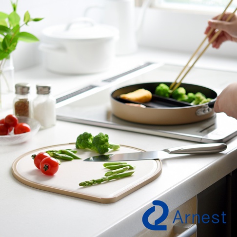 淚滴型白色抗菌料理砧板，邊緣為淺棕色，上面擺放著番茄、荷蘭豆和蘆筍。