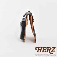 職人手作皮革翻轉雙色直式斜背包，外層為黑色皮革，內裡為棕色皮革，設有拉鍊開口及金屬扣環。