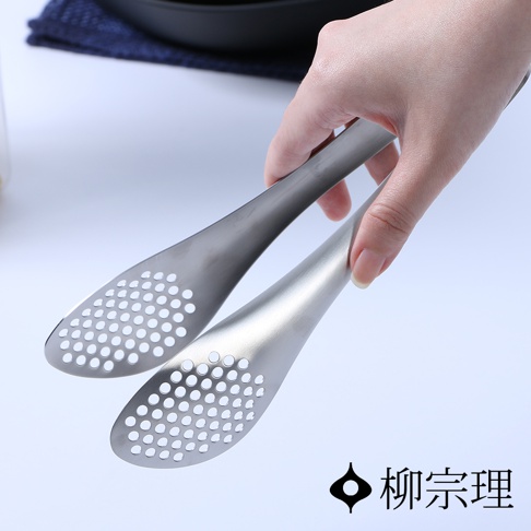 銀色不鏽鋼服務夾，帶有圓形孔洞設計，由手持。