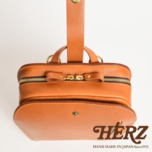 職人手作皮革商務休閒兩用後背包 R-36，呈現經典棕色牛皮革，配有金色拉鍊與釦環，簡約設計適合各種場合。