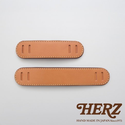 兩件棕色皮革肩墊，一種尺寸較小，另一種尺寸較長，均帶有縫線和用於固定或調整的雙槽孔。