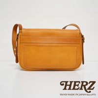 職人手作皮革復古翻蓋郵差包，採用天然皮革材質，呈現溫潤的橘棕色調，包身線條簡潔，附有翻蓋設計與精緻縫線，側面與肩帶亦為皮革材質。