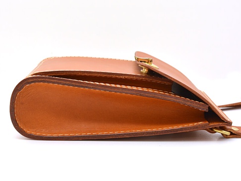 職人手作的棕色皮革厚實單肩包，側邊展示其精緻縫線與金屬釦環，材質厚實且結構穩固。