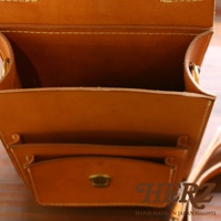 職人手作皮革單肩兩用小方包，採用棕褐色皮革，內有隔層，外部有金屬扣環，展現精緻縫線工藝，適合日常攜帶。