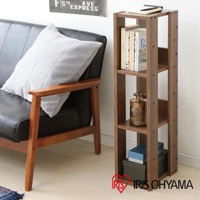 深棕色木質三層收納架，寬度約20公分，架上擺放書籍、玻璃花瓶和紙盒，旁邊為黑色皮質沙發與灰色抱枕。