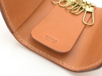 職人手作皮革經典鑰匙包，淺棕色皮革，內有六個金色掛鉤，皮革表面壓印品牌標誌。