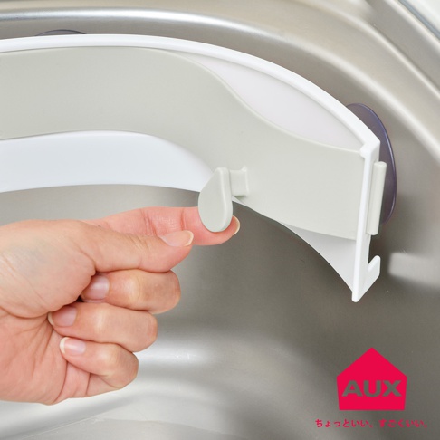 手正操作AUX廚餘架的卡榫，架子固定在流理台上