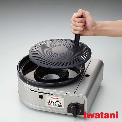 銀色金屬機身、帶有黑色烤網的無煙燒烤爐，烤網中央有旋轉把手，下方有黑色水盤。