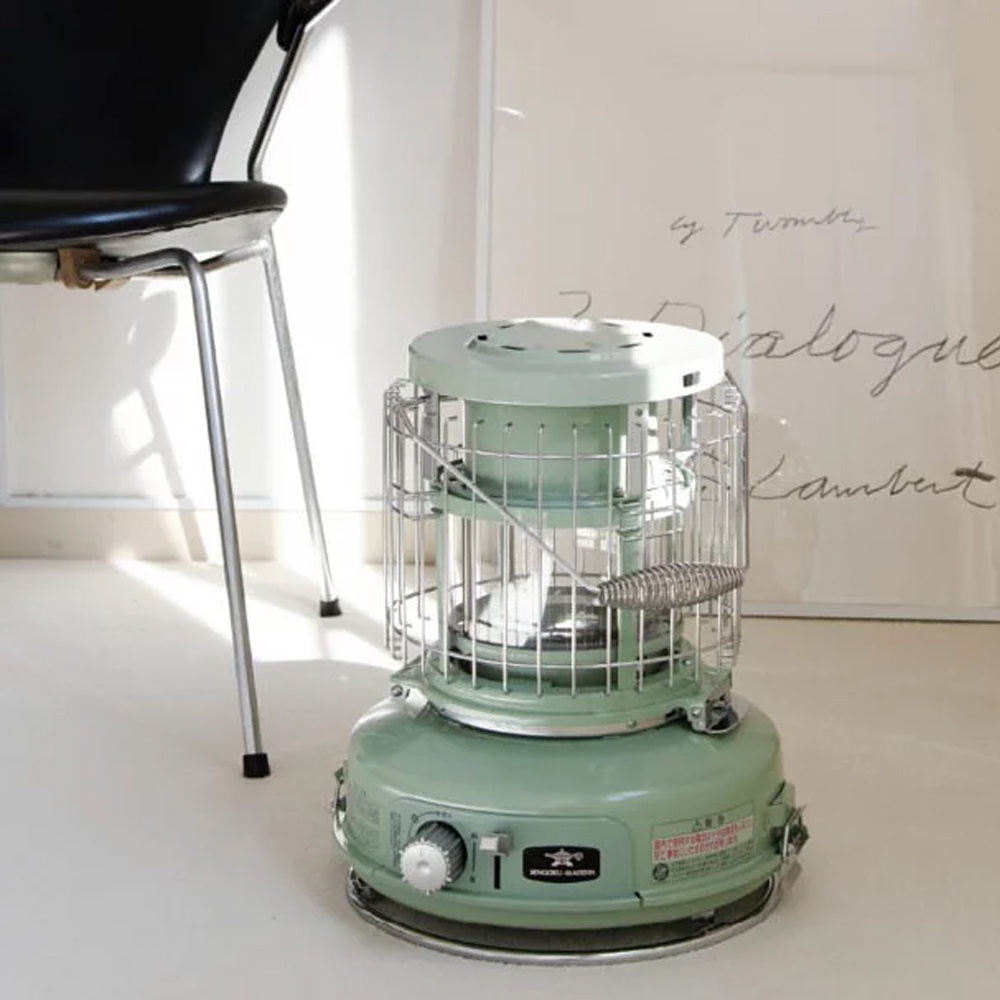 淺綠色卡式瓦斯暖爐，帶有玻璃觀賞窗和銀色金屬護網，底部有調節旋鈕和品牌標誌。