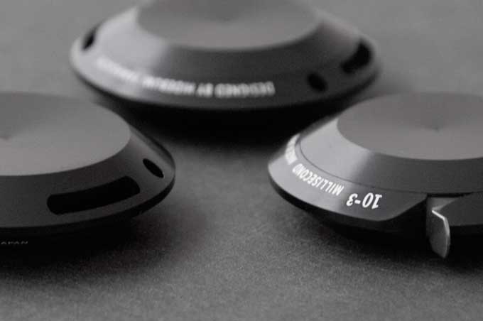 三件黑色鋁製圓形物件，其中一件標有「10-3 MILLISECOND」字樣，另一件標有「DESIGNED BY HORNBY」字樣，表面光滑，有細微的紋理。