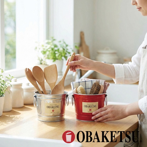 OBAKETSU 品牌手工製多功能迷你桶，左側為銀色桶裝著木製廚房用具，右側為紅色桶內有抹布和刷子。